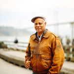 Image of Charles Blackwell wearing a tan jacket with his walkign stick in hand.